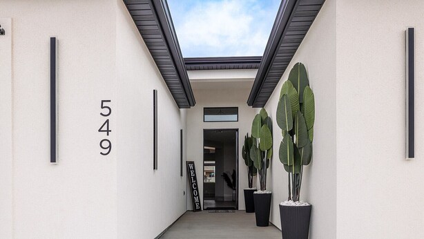 A modern building entrance with a number '549' on the wall, a welcome sign, and large potted plants. - The Mustang Collection 49 Newly Built Desert Retreat (Page)