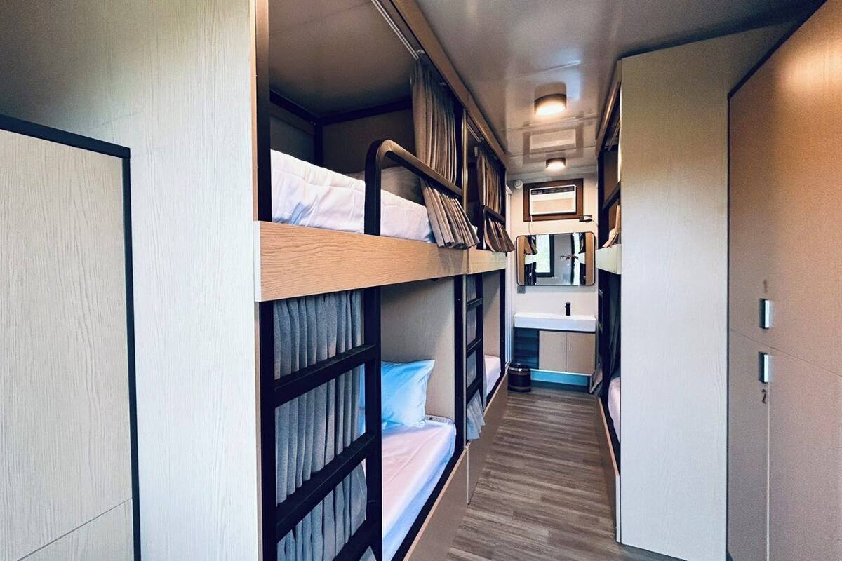A narrow hallway with bunk beds on one side and a small kitchenette on the other.