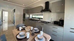 A modern kitchen with a dining area, featuring a large island, built-in appliances, and a view to the outdoors. - Luxurious Villa in La Marsa Elegance Comfort & Ideal Location (La Marsa)