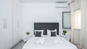 A modern hotel room with a large bed, white walls, a dark headboard, and a window with curtains. - Luxurious Villa in La Marsa Elegance Comfort & Ideal Location (La Marsa)