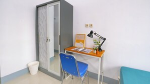 Una habitación pequeña y ordenada con un escritorio, una silla y otra silla azul.