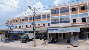 Un edificio de varios pisos con un espacio comercial en la planta baja, que incluye una gasolinera y una tienda llamada "dil Home".