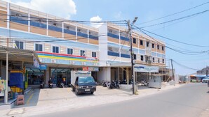 Un edificio de varios pisos con un local comercial en la planta baja, que incluye un área de estacionamiento y un escaparate visible.