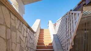 A stone staircase leading upwards, flanked by a stone wall on one side and a metal fence on the other. - Elegant Ground-Floor Apartment in Porto Cesareo – Design moderno Vicino al mare (Porto Cesareo)