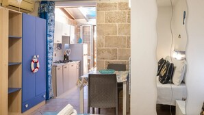 A compact kitchen with a dining area, a wardrobe, and a bed. - Elegant Ground-Floor Apartment in Porto Cesareo – Design moderno Vicino al mare (Porto Cesareo)