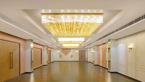 A spacious hotel corridor with a large chandelier, wooden doors, and recessed lighting. - Enrise By Sayaji Somnath (Veraval)