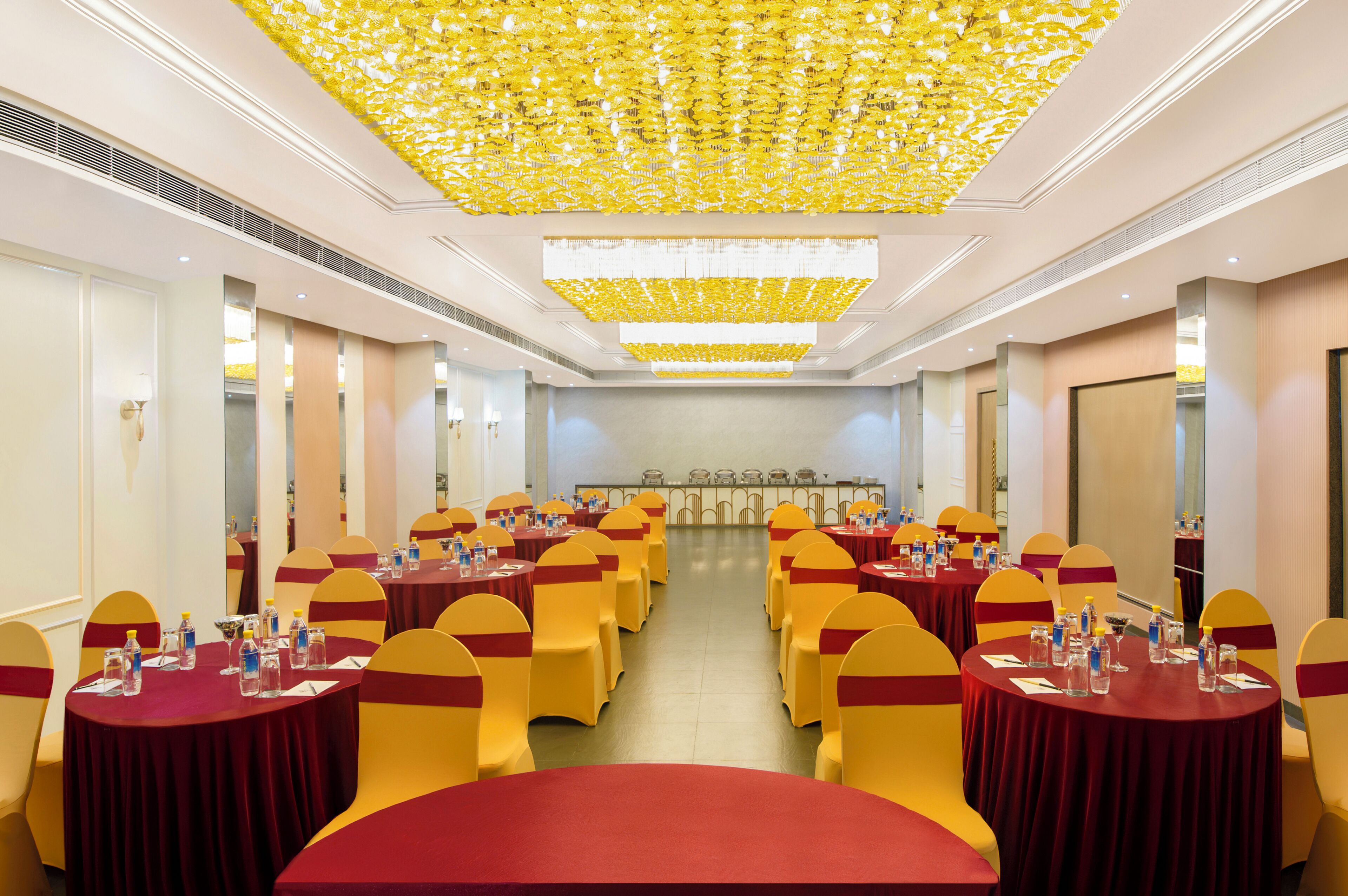 Un salón de conferencias con mesas redondas, sillas amarillas y un techo con diseño amarillo.