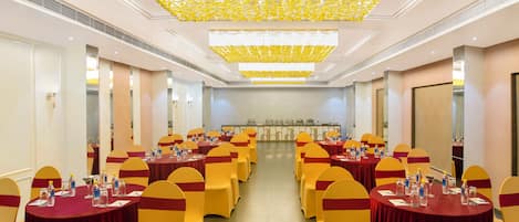 A conference room with round tables, yellow chairs, and a ceiling with a yellow pattern.