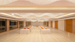 A spacious hall with rows of tables, a chandelier, and a modern ceiling design. - Enrise By Sayaji Somnath (Veraval)