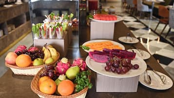 Una mesa de buffet con diversas frutas y verduras, incluyendo naranjas, uvas y pitahaya.