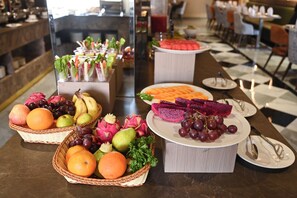 A buffet table with various fruits and vegetables, including oranges, grapes, and dragon fruit. - Enrise By Sayaji Somnath (Veraval)