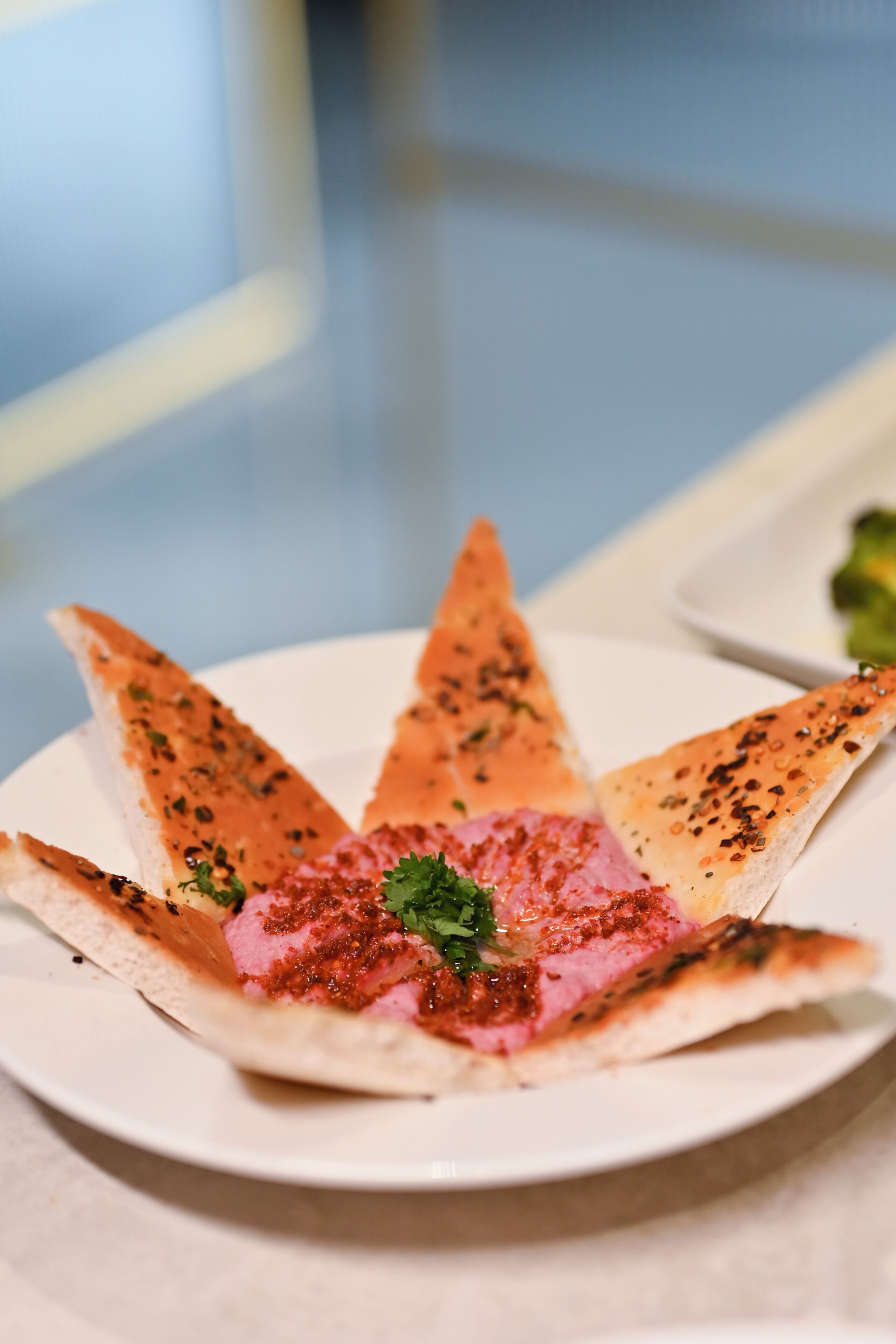 Een bord met een gerecht, mogelijk met een roze vulling en kruiden, op een wit bord.
