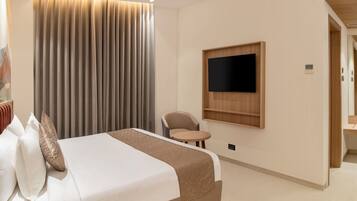 Habitación de hotel con una cama, televisión instalada en la pared, una mesita pequeña y una silla.