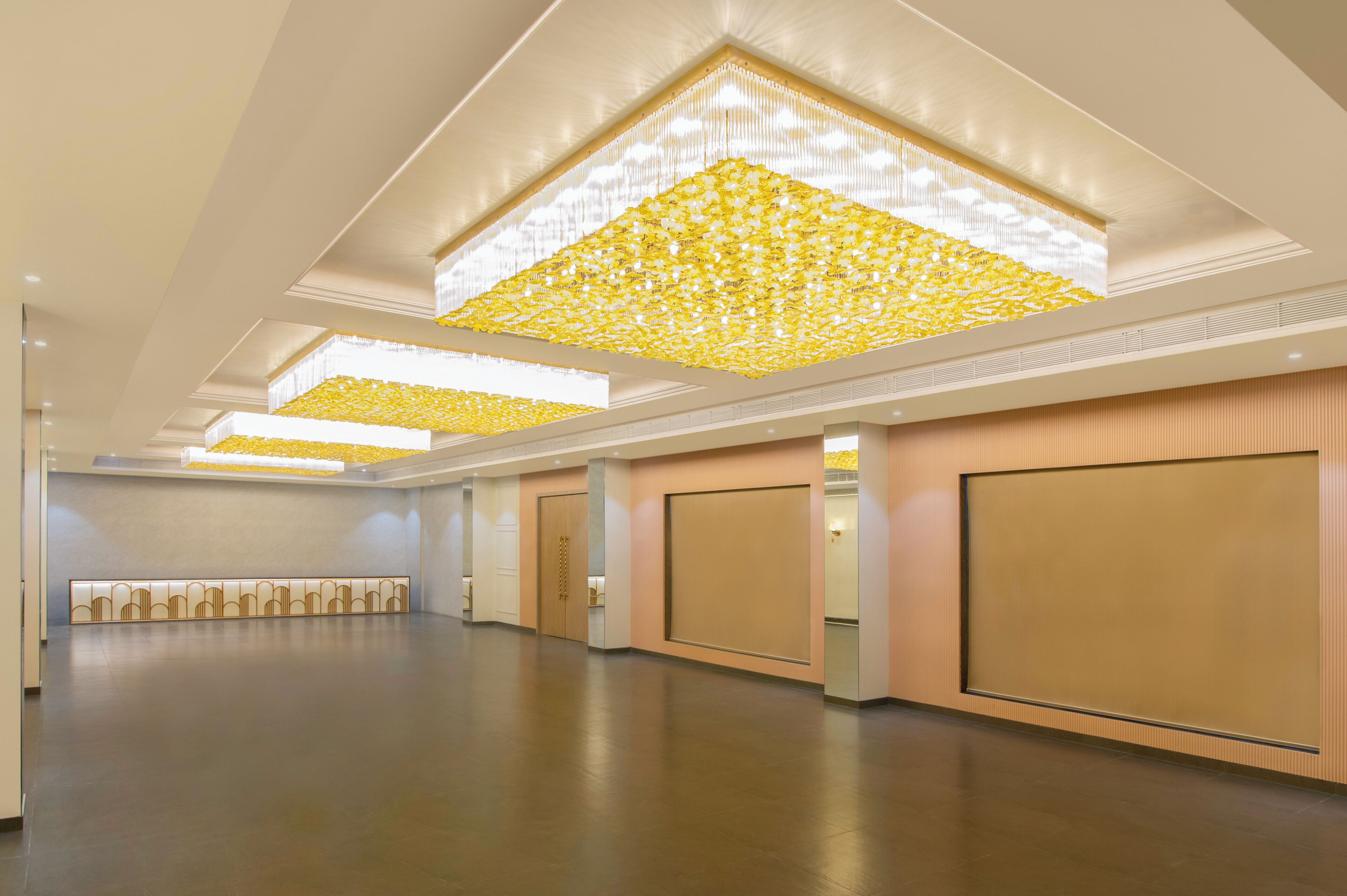 A spacious hotel lobby with a high ceiling, recessed lighting, and a patterned ceiling design.