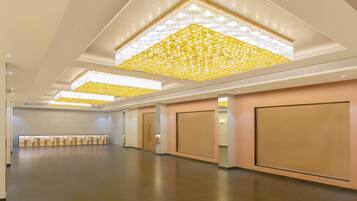 A spacious hotel lobby with a high ceiling, recessed lighting, and a patterned ceiling design.