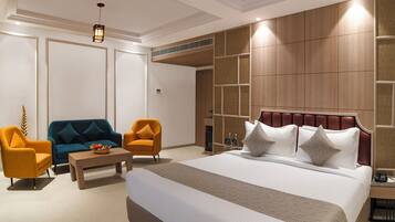 A hotel room with a large bed, two armchairs, a coffee table, and a decorative wall panel.