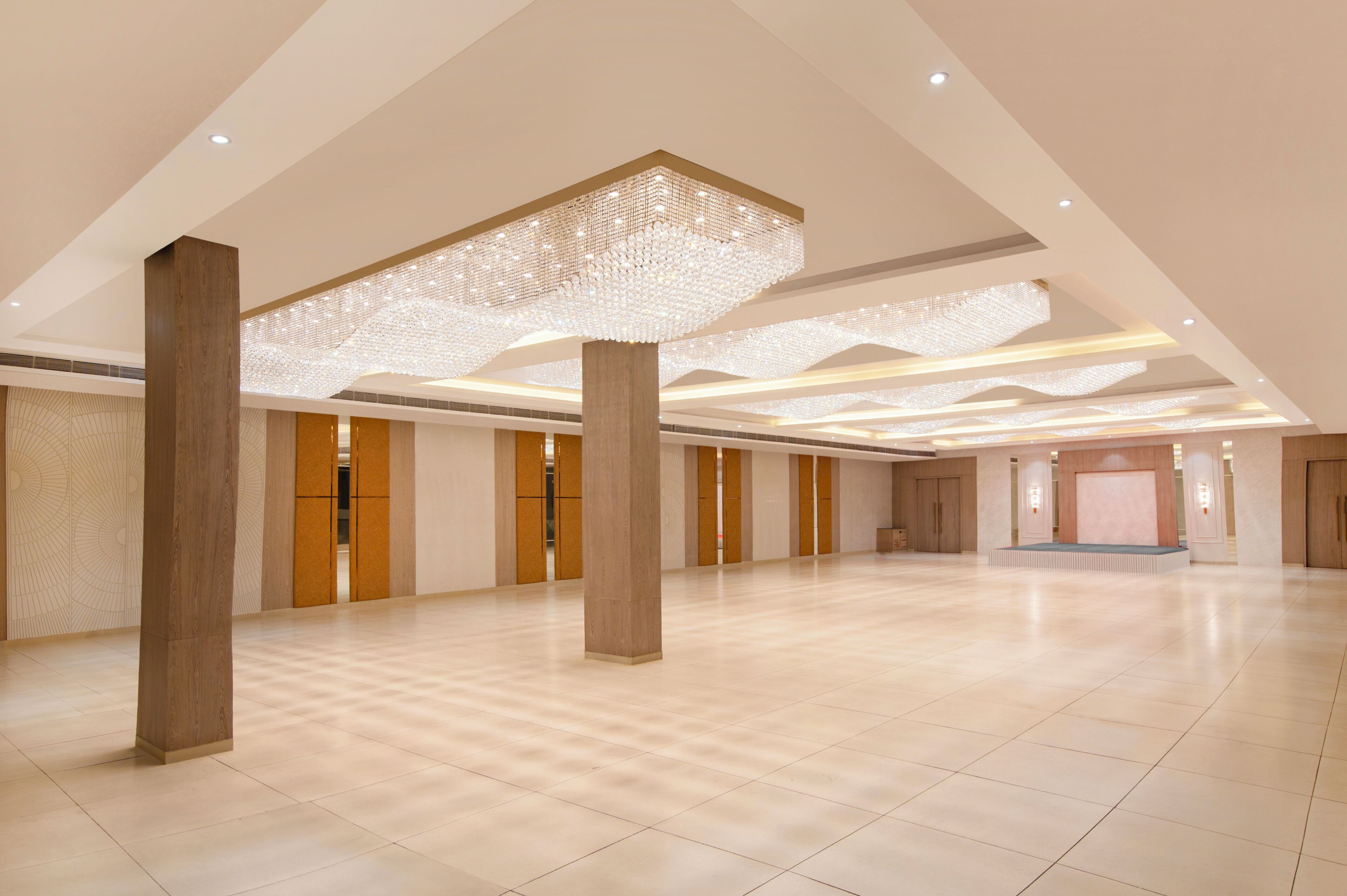 Un espacioso vestíbulo de hotel con techos altos, grandes columnas y un moderno candelabro.