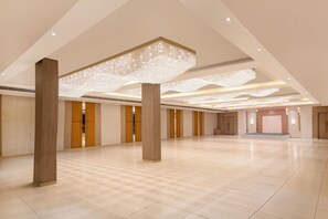 Un espacioso vestíbulo de hotel con techos altos, grandes columnas y un moderno candelabro.