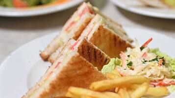 A dining table with plates of food, including sandwiches and fries.