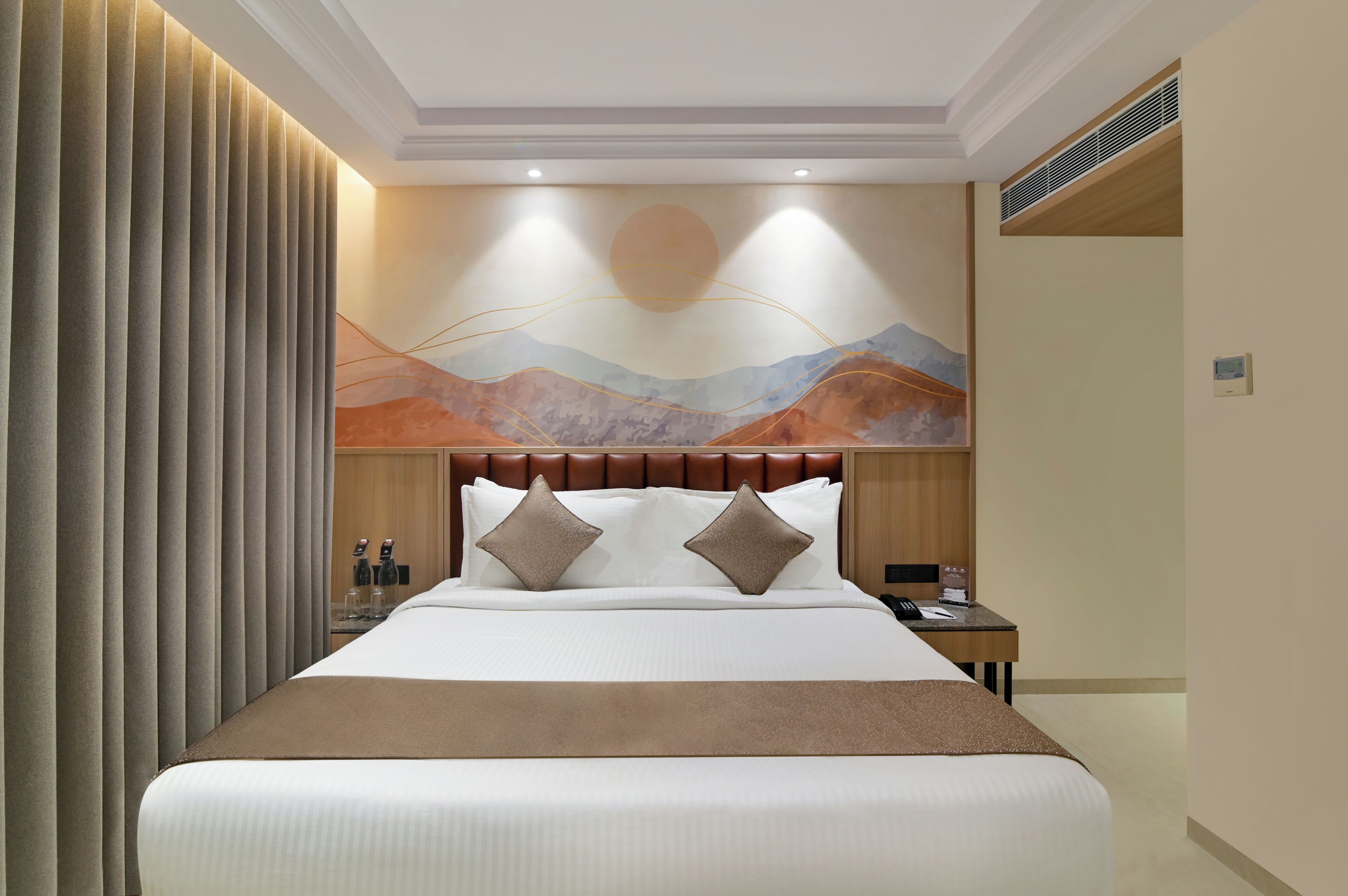 Une chambre d’hôtel comprenant un lit, une table de chevet, une œuvre d’art accrochée au mur et une fenêtre avec des stores.