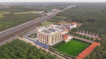 Un hotel grande con varios pisos, una piscina y una carretera aledaña.