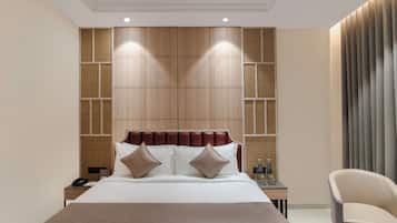 Habitación de hotel con una cama grande, una mesita de noche, una silla y un panel de madera en la pared.