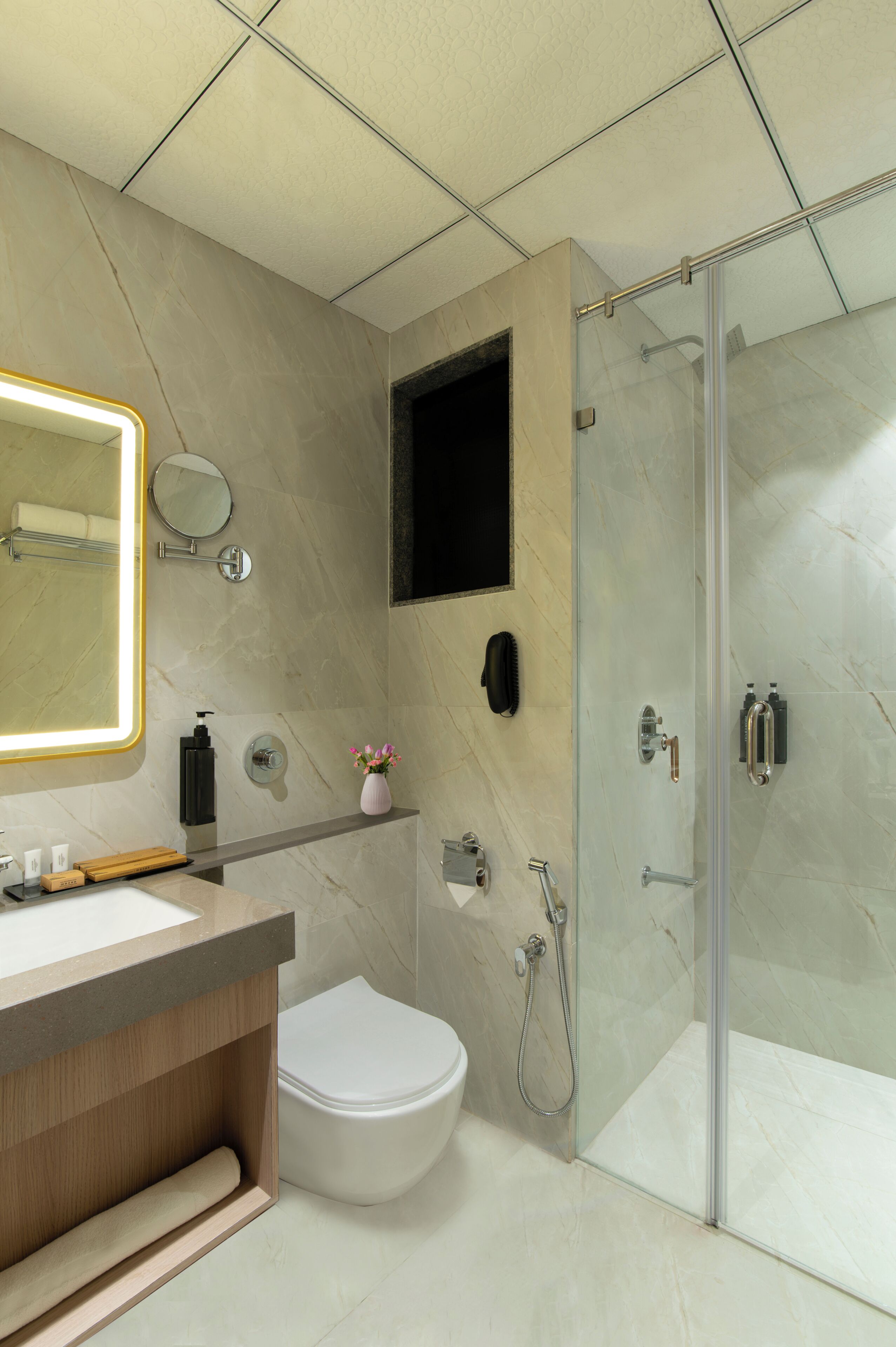 Ein modernes Badezimmer mit Toilette, Waschbecken, Spiegel, Dusche und Handtuchhalter.
