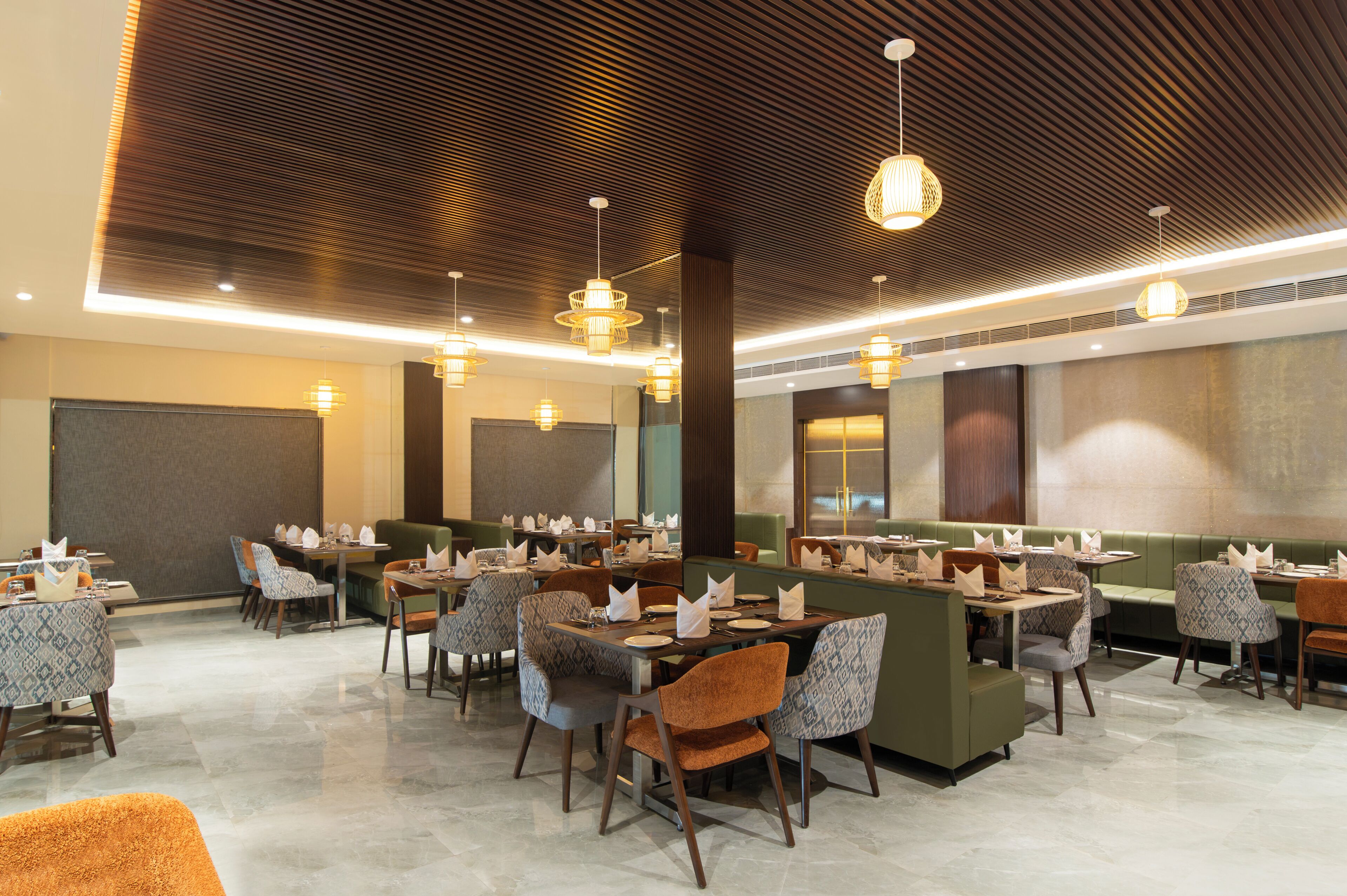 Een restaurant met meerdere tafels en zitjes, een versierde plafond en hanglampen.