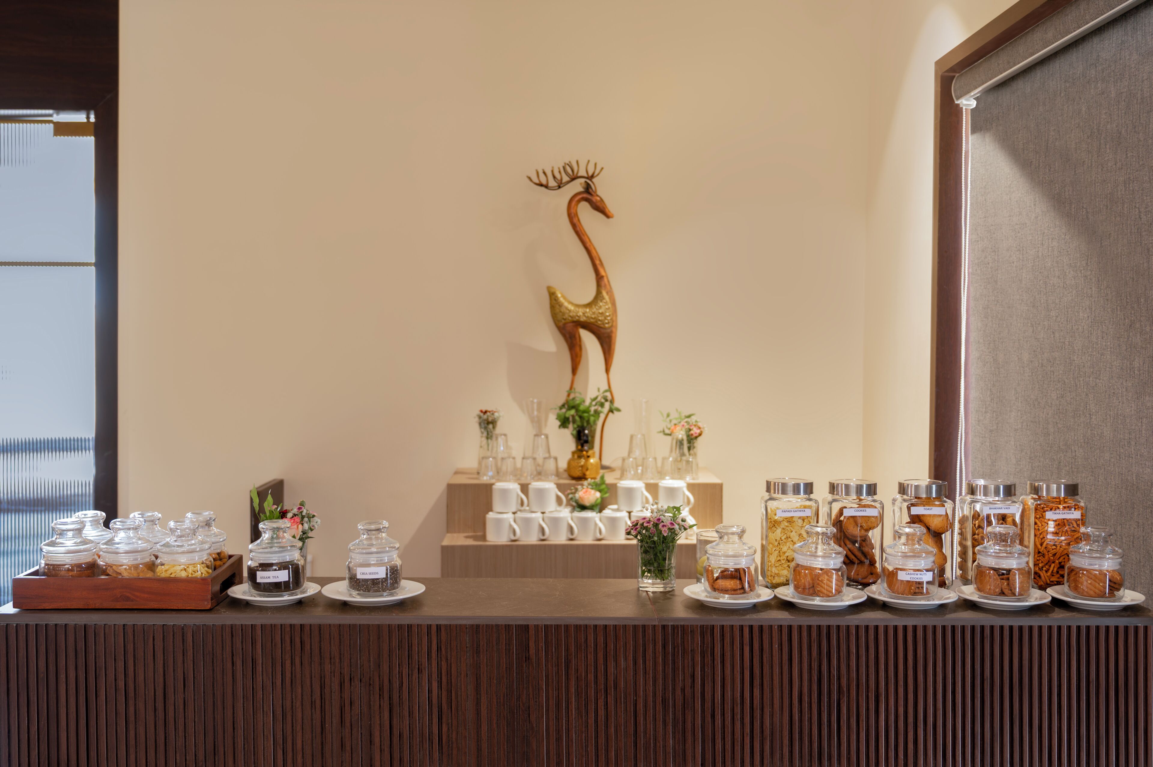 A buffet setup with various food containers, a decorative swan, and a row of white cups.