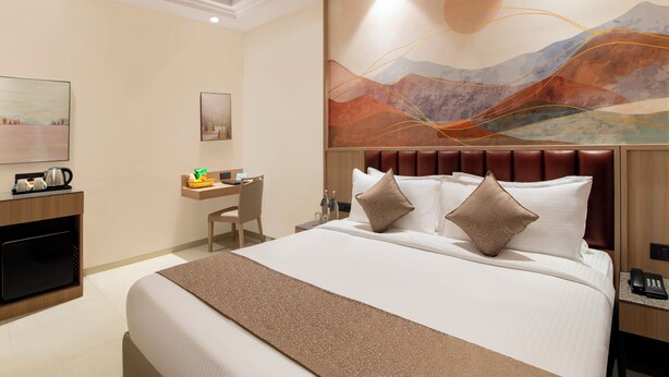 A hotel room with a large bed, a desk, and a painting on the wall. - Enrise By Sayaji Somnath (Veraval)