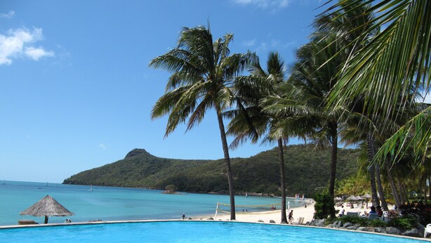 A clear blue pool with a view of the sea and a mountain in the background. - NEW Luxury Hamilton Island Estate (Whitsundays)