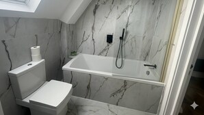 A modern bathroom with a skylight, a bathtub, and a toilet. - Dippen Hall Charm - Minutes From London Gatwick (Lingfield)