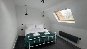 A bedroom with a bed, a skylight, and a radiator. - Dippen Hall Charm - Minutes From London Gatwick (Lingfield)