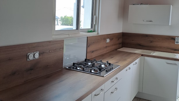 Eine Küche mit Gasherd, Holzausziehtisch, weißen Schränken und einem Fenster mit Blick.