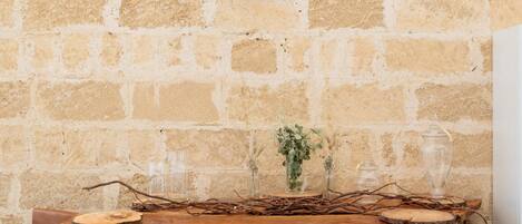 A rustic outdoor seating area with a stone wall backdrop, wooden barrels, and a decorative wall piece.