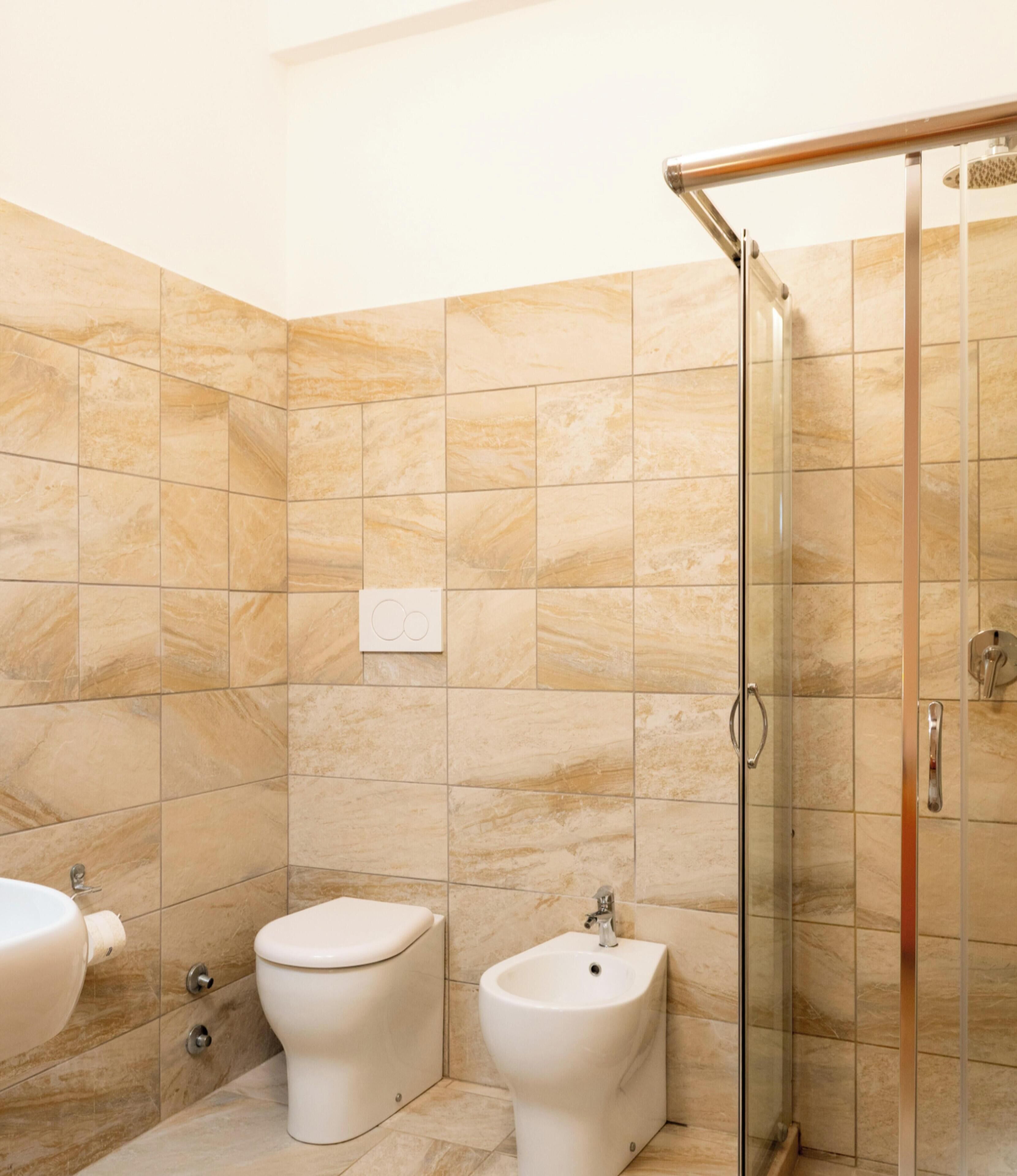 A bathroom with a glass shower enclosure, a toilet, and a bidet.