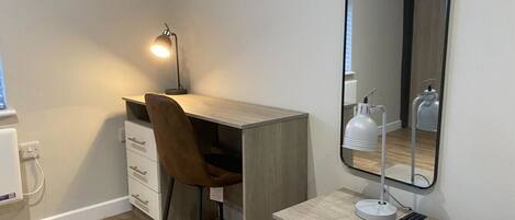 A small, modern room with a desk, chair, and a mirror.