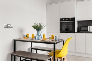 A modern kitchen with white cabinetry, a black oven, and a microwave. - Spacious 4-Bed Home Near Leeds Centre & Links (West Yorkshire)