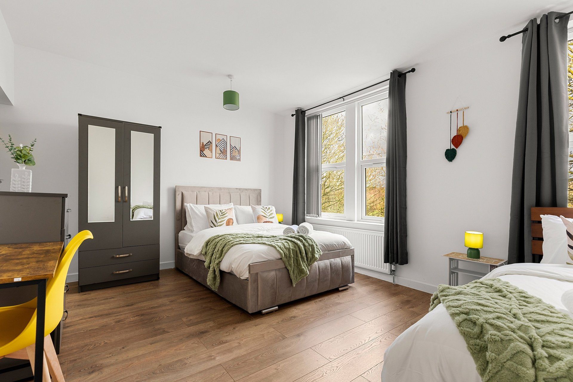 A bedroom with a bed, a desk, a chair, a window, and a radiator.