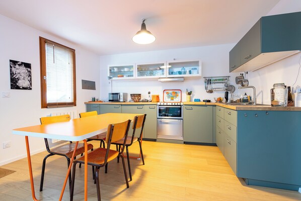 Une cuisine compacte comprenant une table et des chaises, des placards intégrés et une cuisinière.