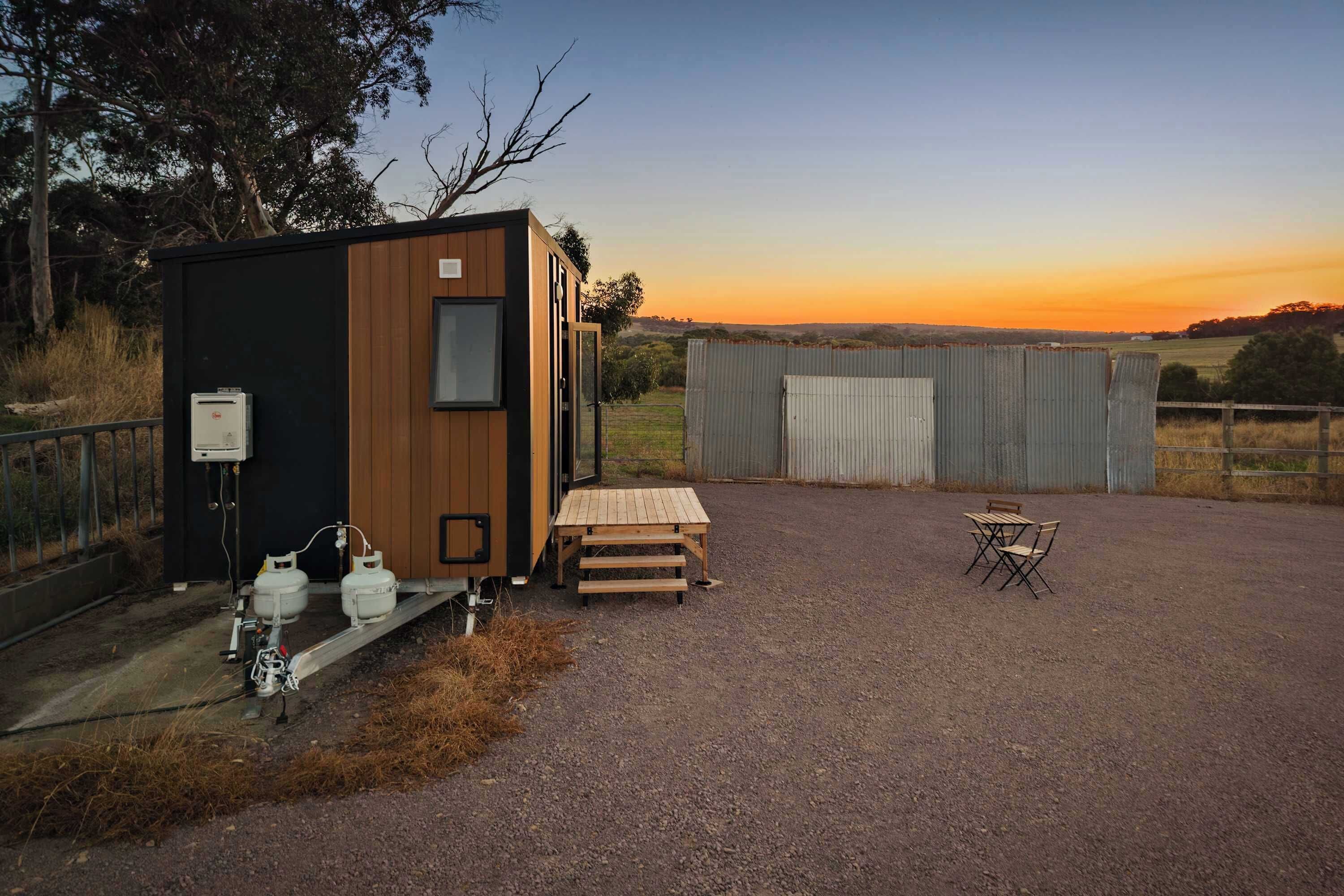 Une petite cabane au revêtement extérieur en bois, avec une petite table et un banc.
