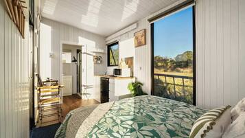A bedroom with a bed, a desk, a chair, a window, and a view of the outdoors.