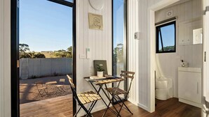 Une pièce avec une table et des chaises en bois, une vue sur l’extérieur, une fenêtre et un meuble blanc.