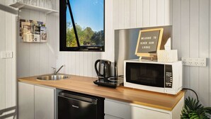 Une cuisine avec un plan de travail en bois, un évier, un lave-vaisselle, une machine à café, un four à micro-ondes et un panneau d’accueil.