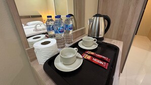 A hotel room with a tray containing a cup, saucer, two Nestle PureLife water bottles, a roll of toilet paper, a kettle, and a packet of Nescafe instant coffee. - Lexis Residence - Newly Renovated Rooms (Tambon Patong)