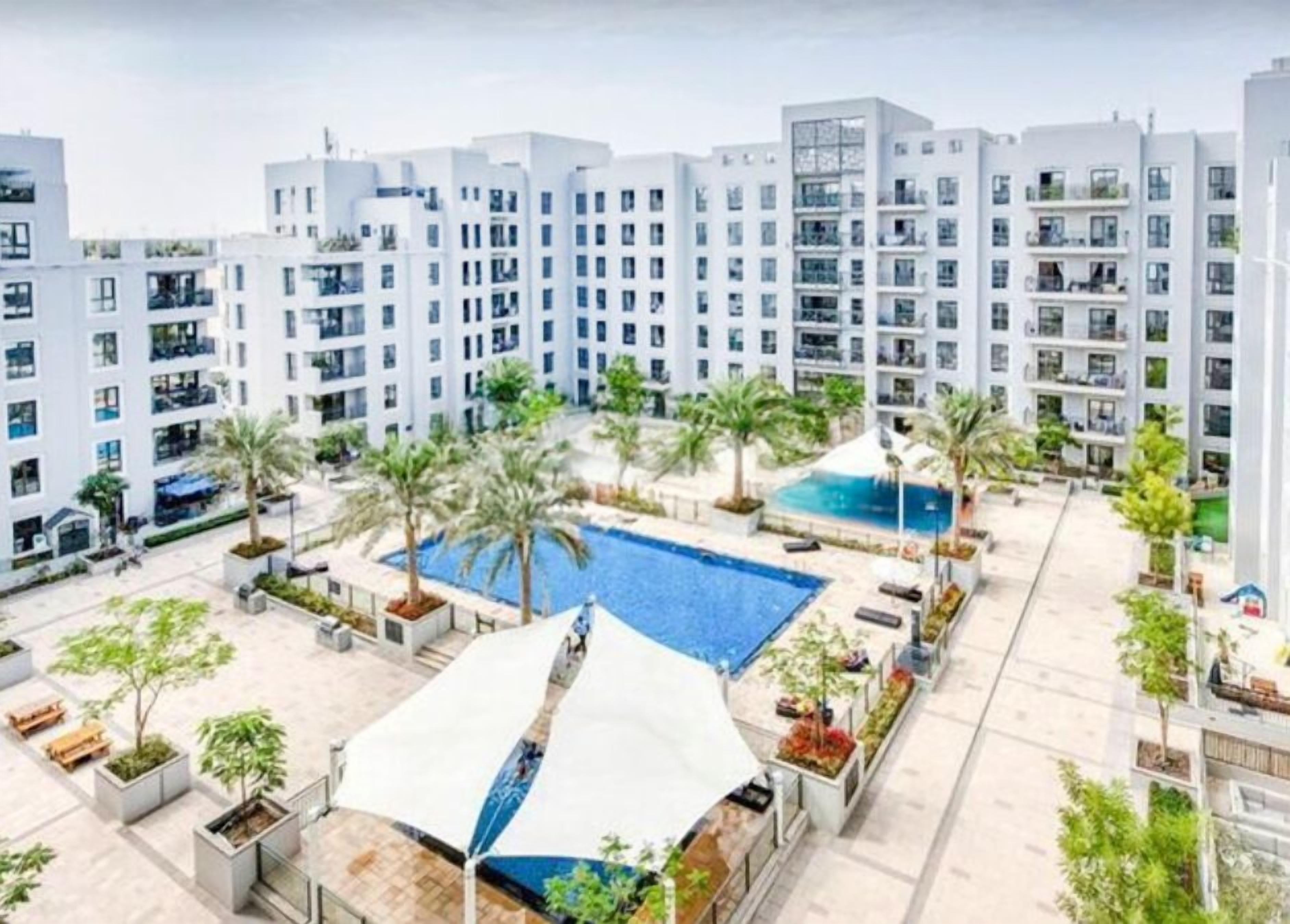 A modern residential building with a rooftop pool and surrounding greenery.