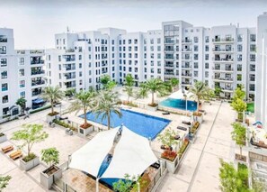A modern residential building with a rooftop pool and surrounding greenery. - Bloomfields Cozy 1br Apt Town (Dubai)
