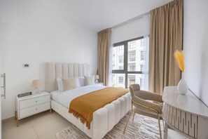 A modern bedroom with a bed, bedside tables, a chair, and a view of the outside. - Bloomfields Cozy 1br Apt Town (Dubai)