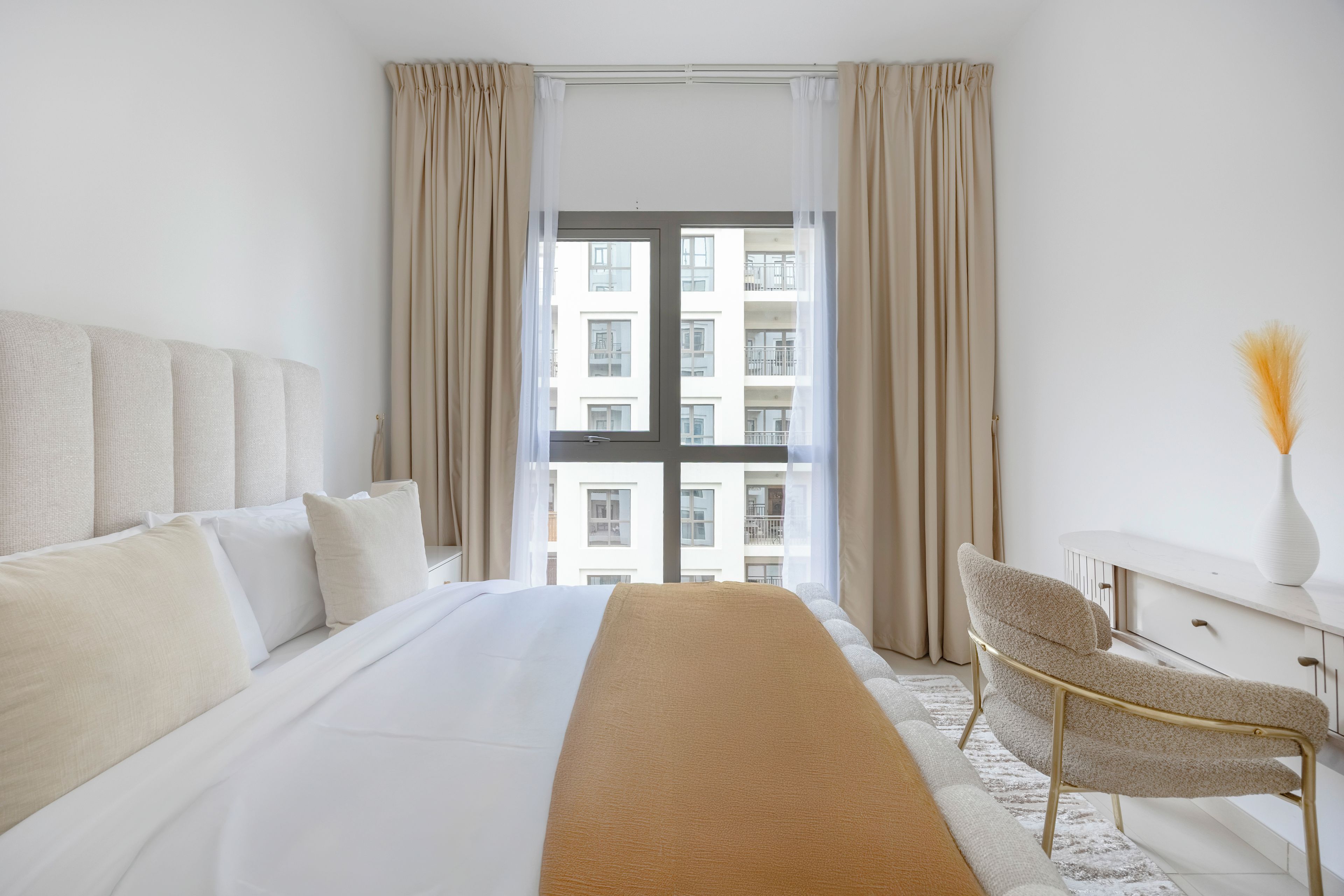 Habitación de hotel con una cama grande, un escritorio, una silla y vistas a un edificio desde la ventana.