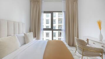 Habitación de hotel con una cama grande, un escritorio, una silla y vistas a un edificio desde la ventana.